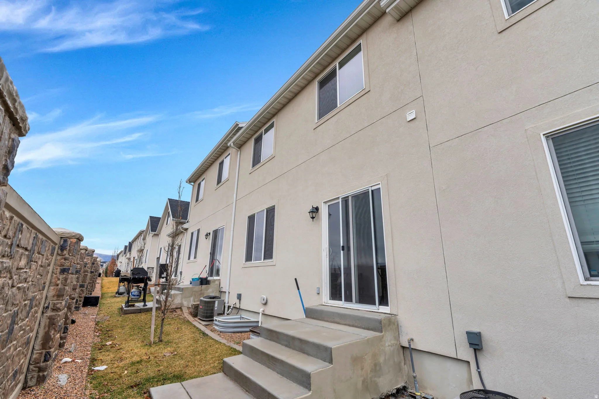 View of side of property featuring stucco siding, entry steps, and a yard