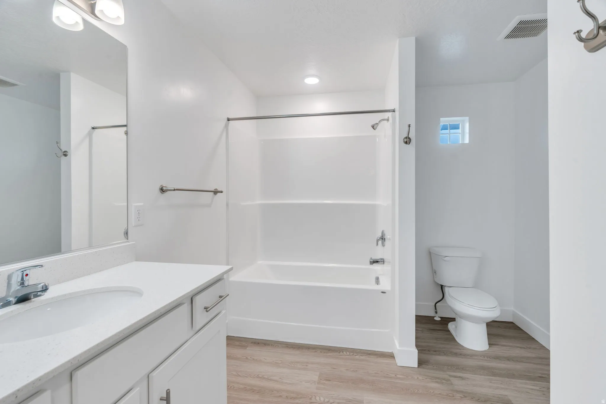 Full bath with light wood finished floors, vanity, and tub / shower combination
