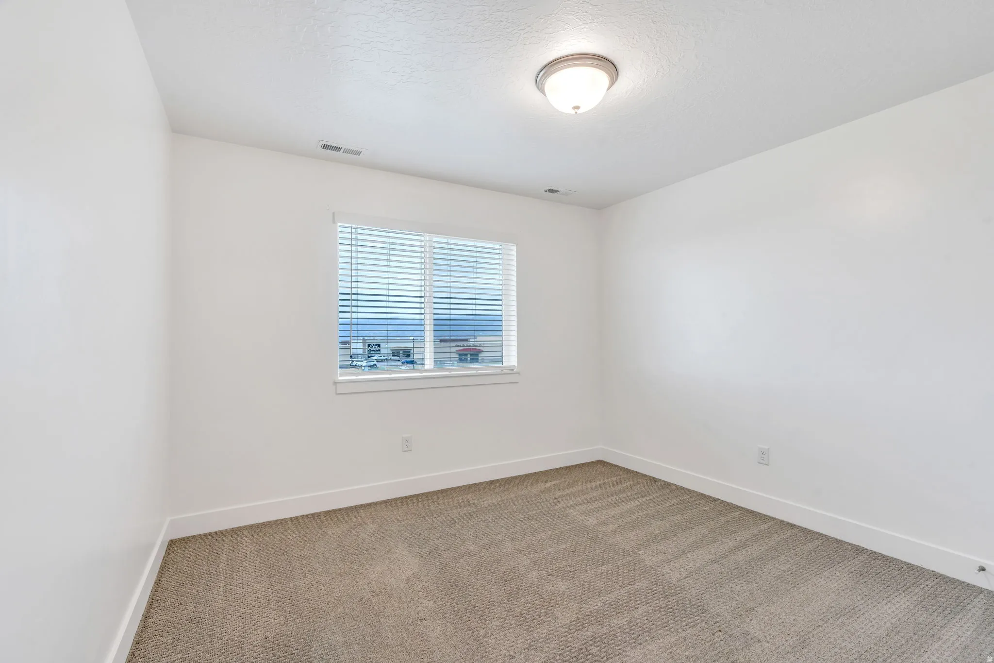 Empty room with carpet flooring and a textured ceiling