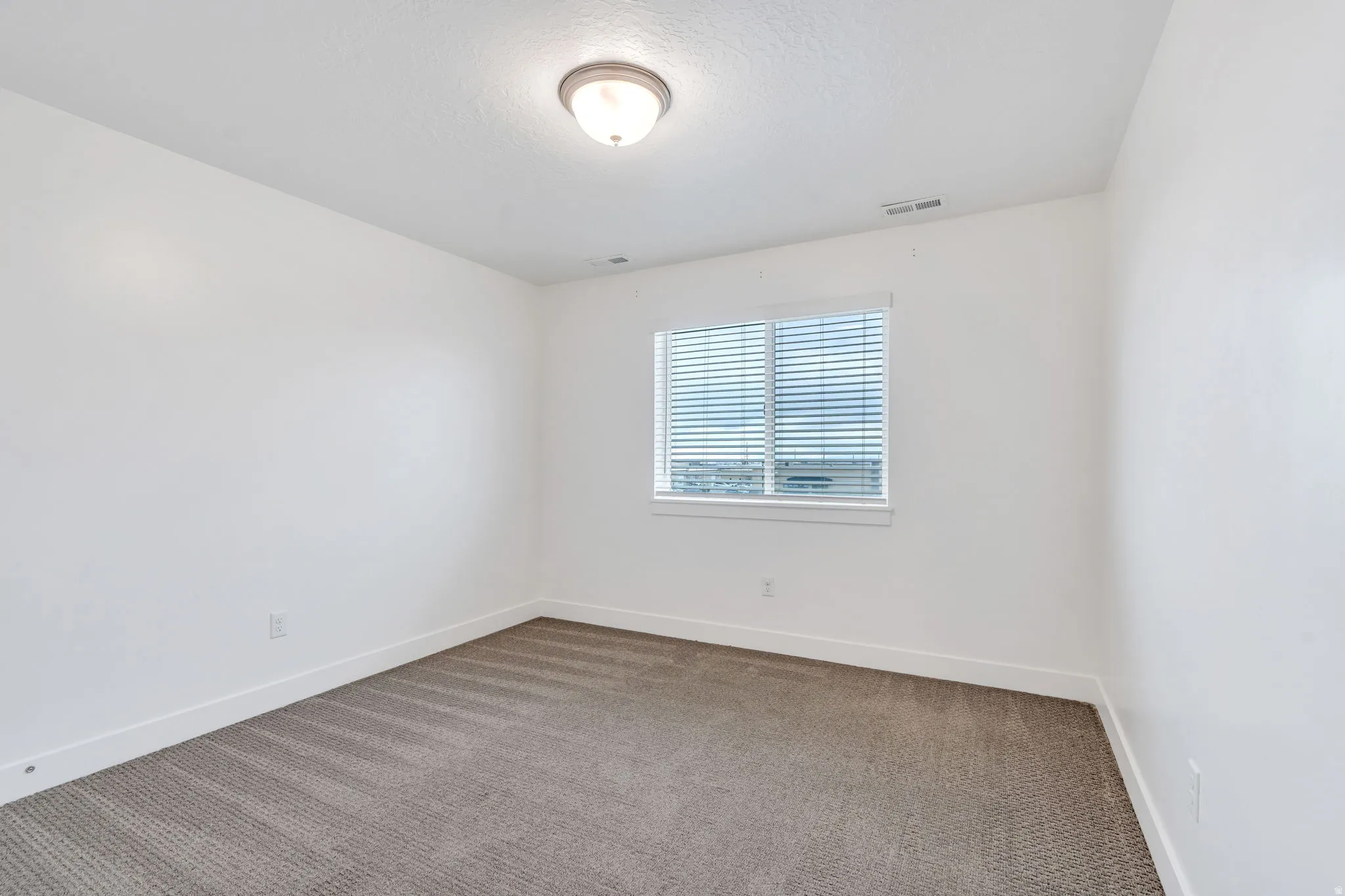 Carpeted empty room with baseboards and a textured ceiling