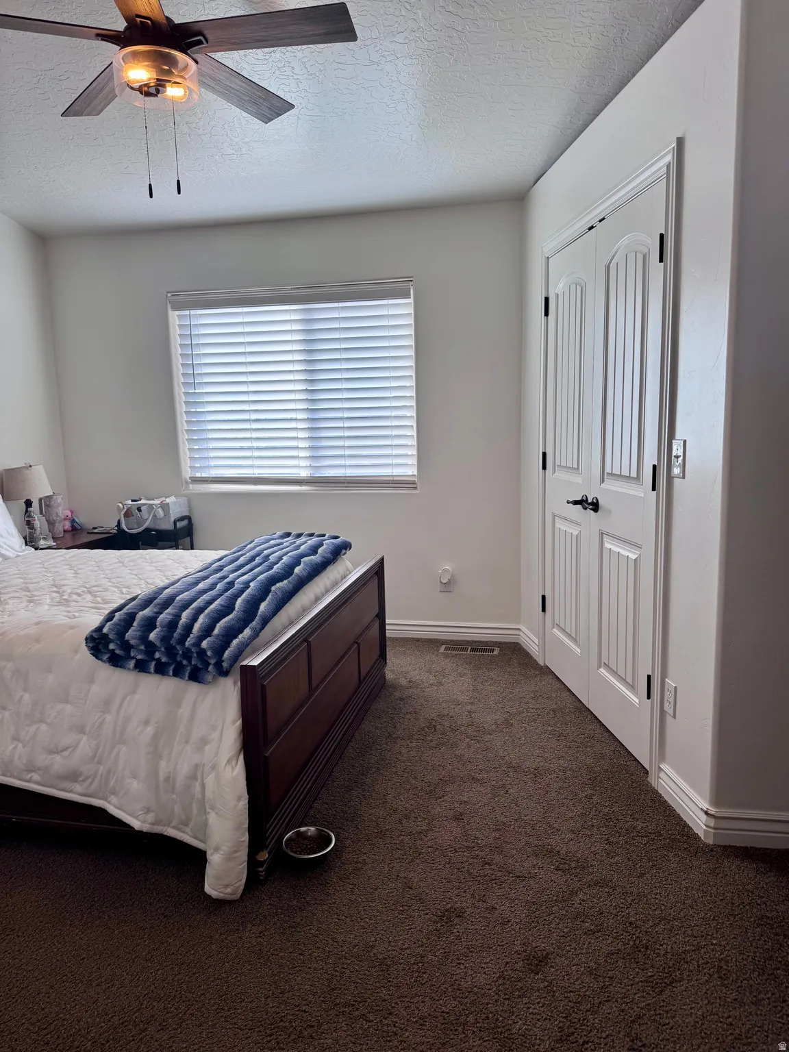Bedroom featuring a textured ceiling, dark colored carpet, and ceiling fan