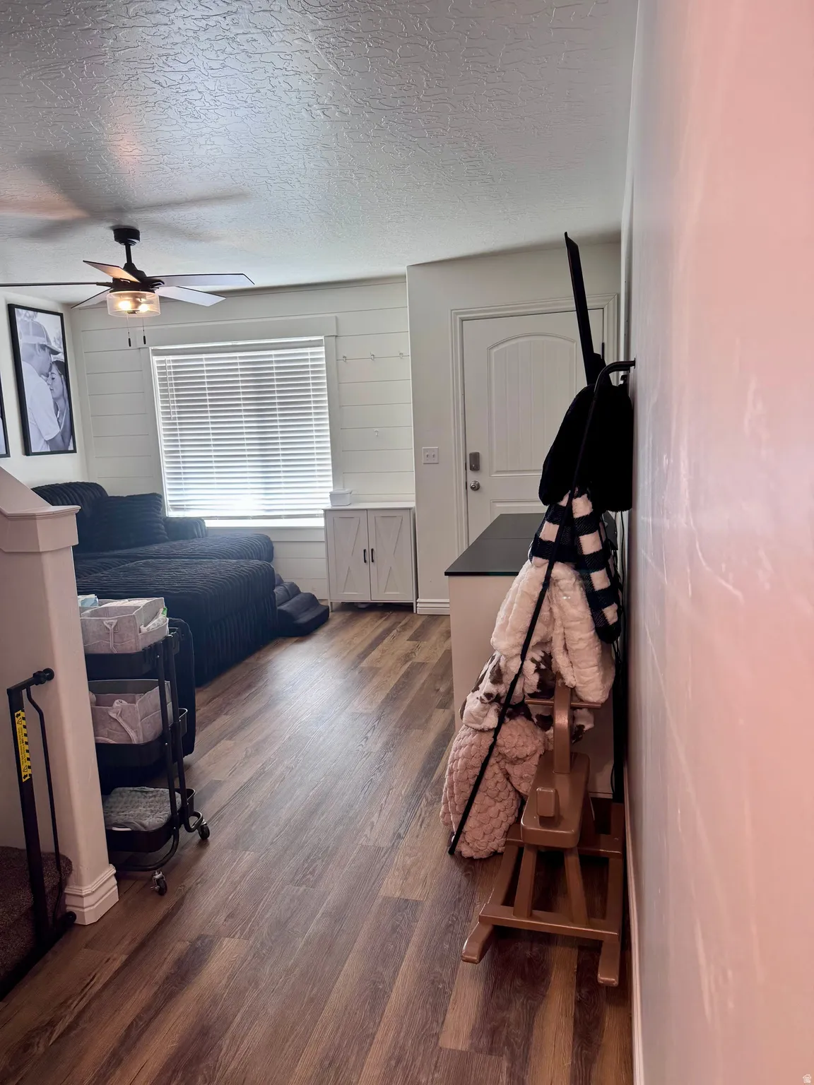 Bedroom featuring wooden walls, dark wood finished floors, a textured ceiling, and a ceiling fan
