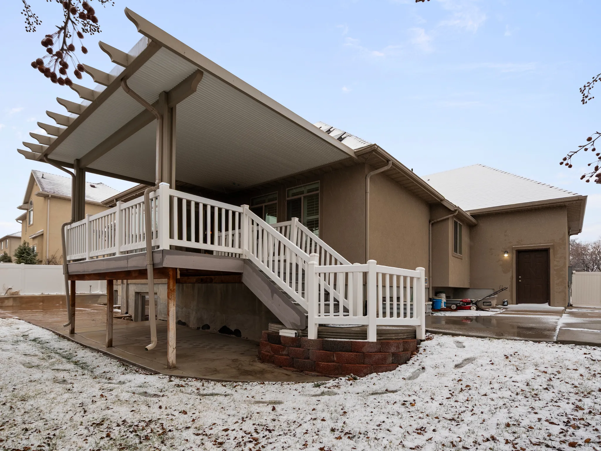Snow covered back of property with a patio area and a deck