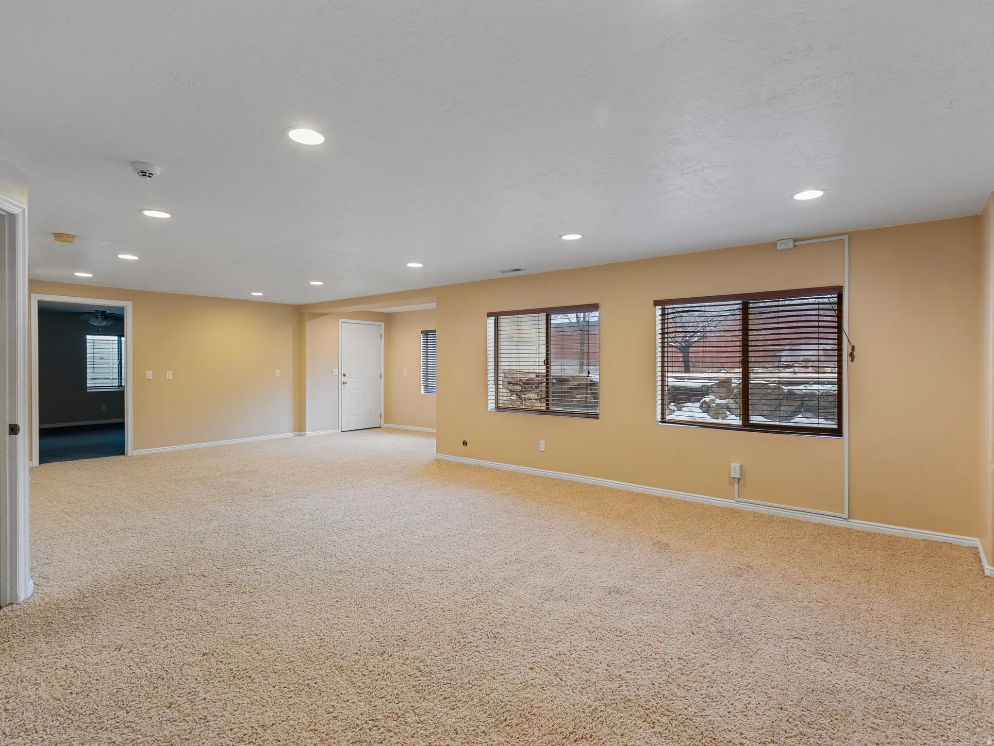 Empty room with light colored carpet and recessed lighting