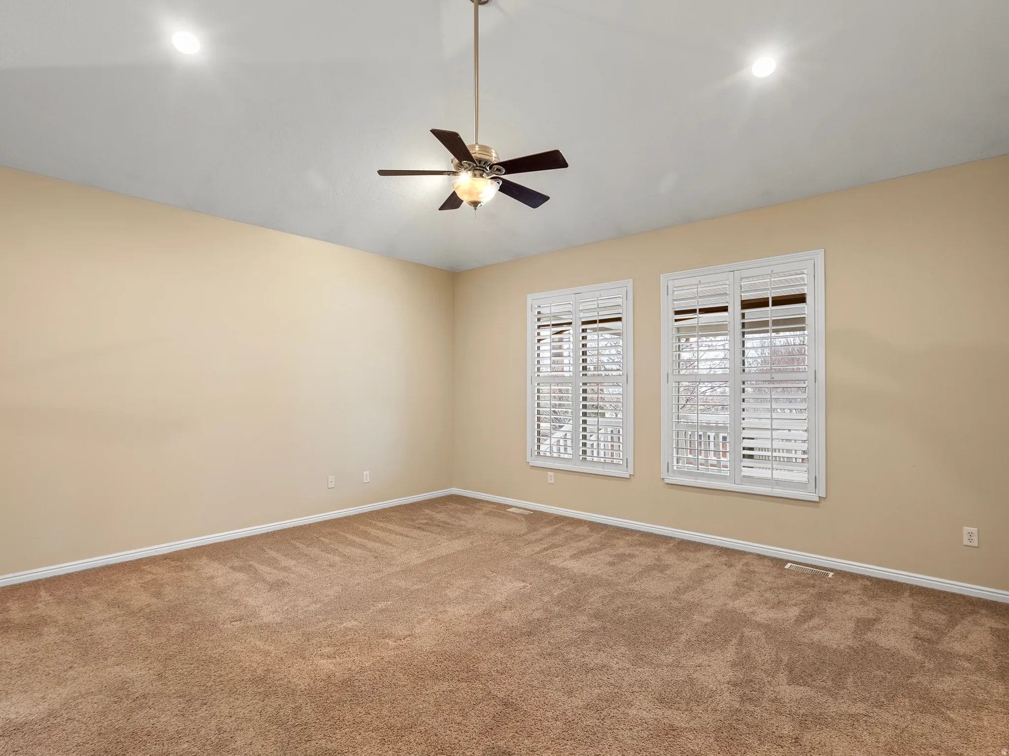 Carpeted spare room with a ceiling fan and lofted ceiling