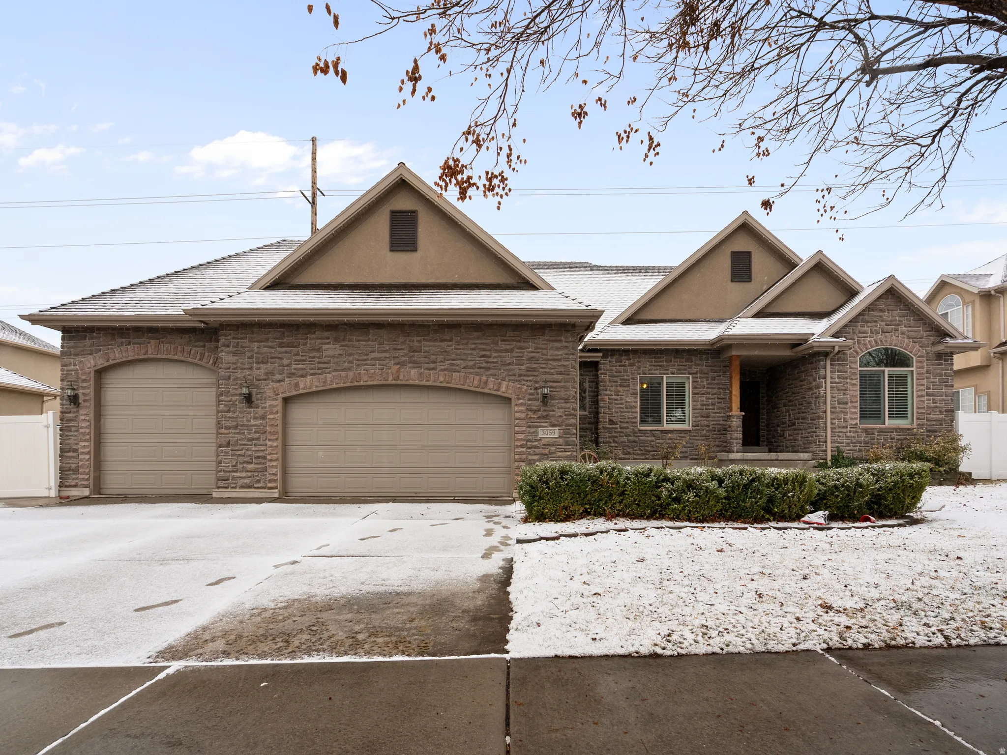 View of front facade featuring driveway, a garage, stone siding, and stucco siding