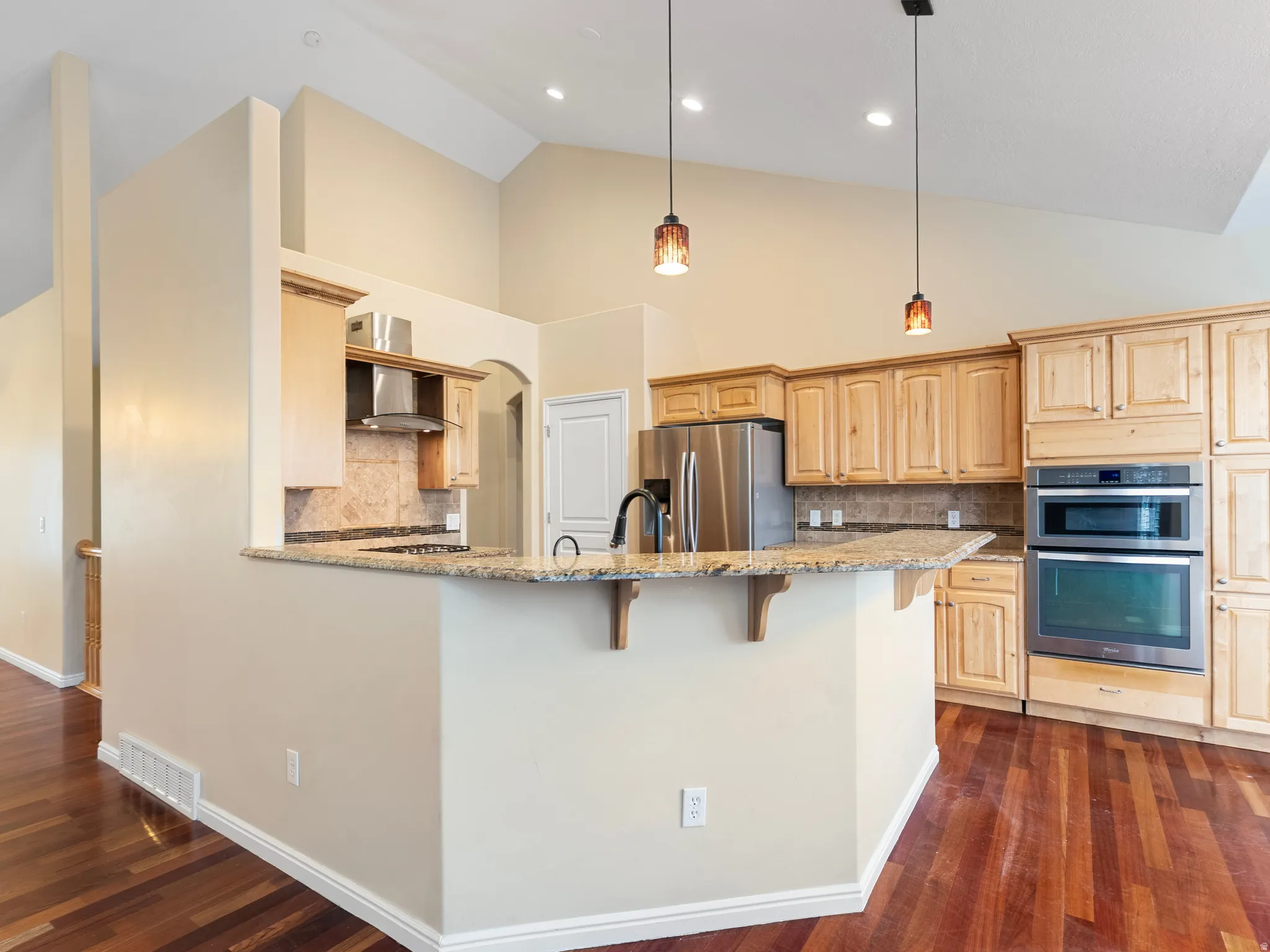 Kitchen with tasteful backsplash, light wood finish cabinetry, a breakfast bar, stainless steel appliances, and light stone countertops