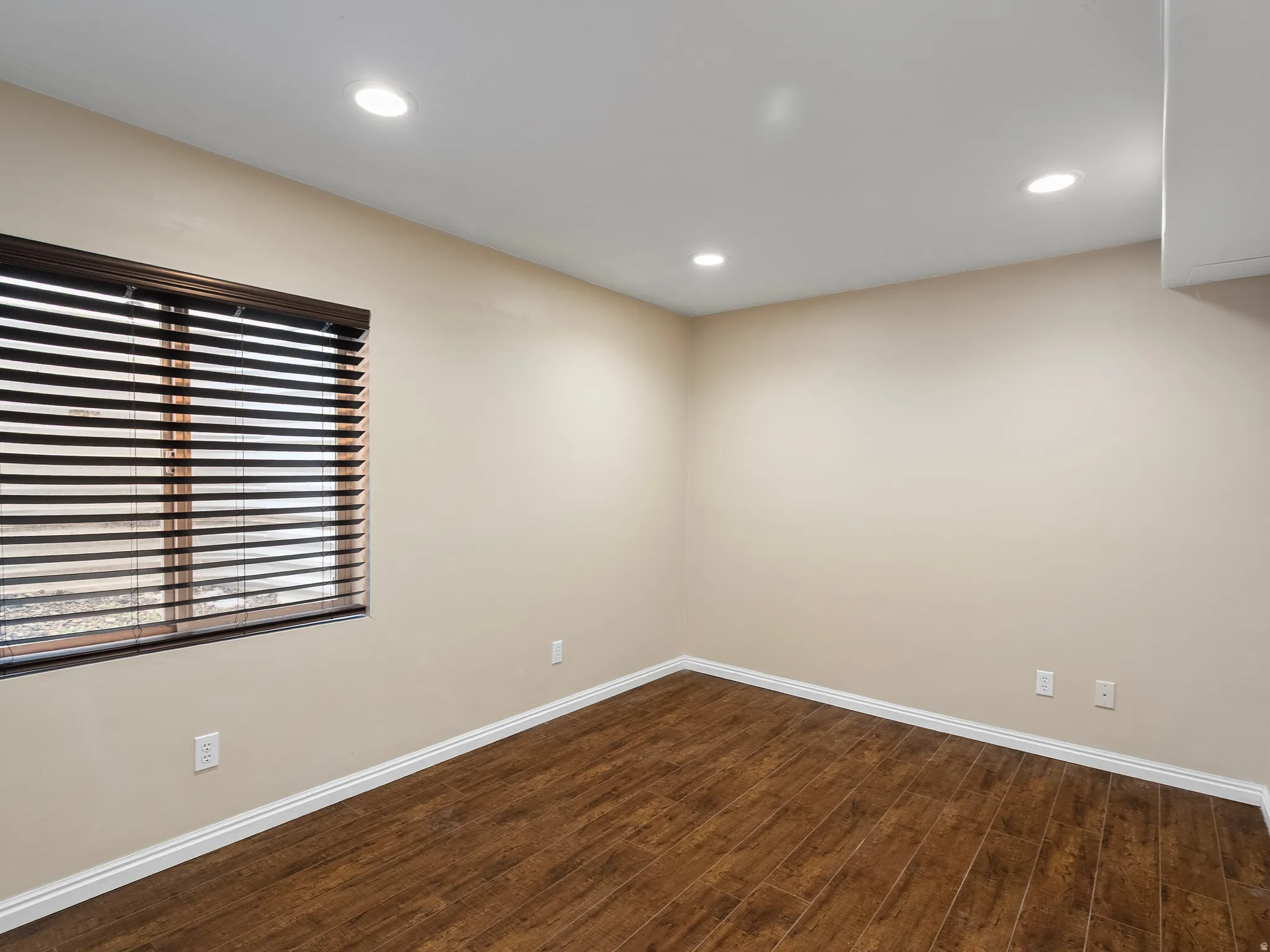 Spare room featuring dark wood-style flooring and recessed lighting