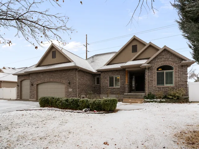 View of front facade featuring a garage, stone siding, stucco siding, and driveway