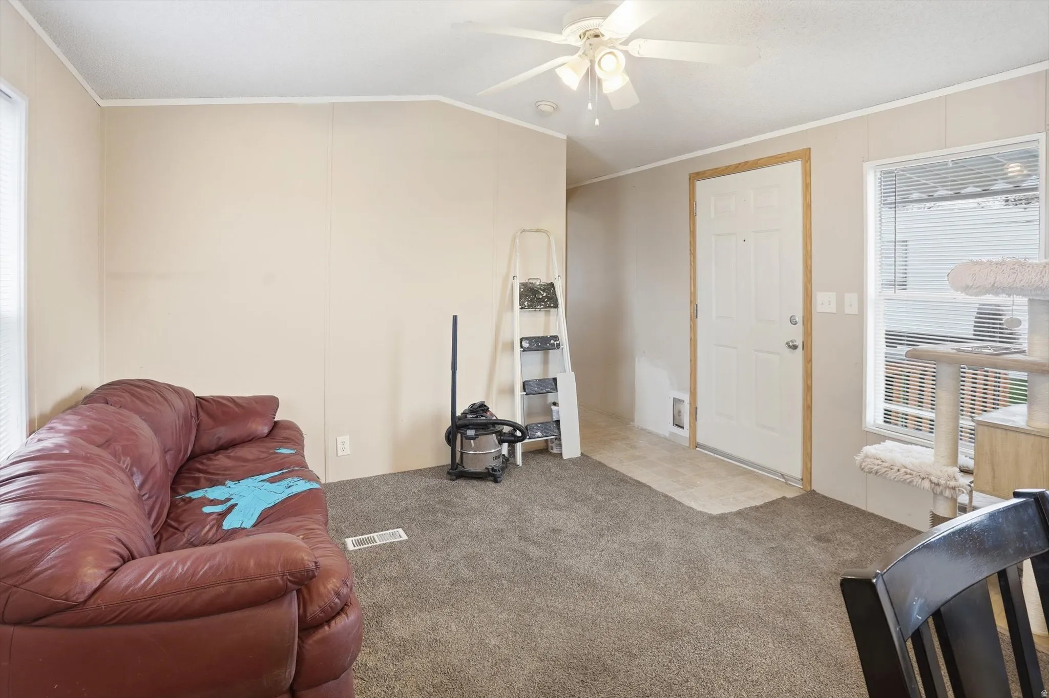 Carpeted living room with plenty of natural light, crown molding, a ceiling fan, and vaulted ceiling