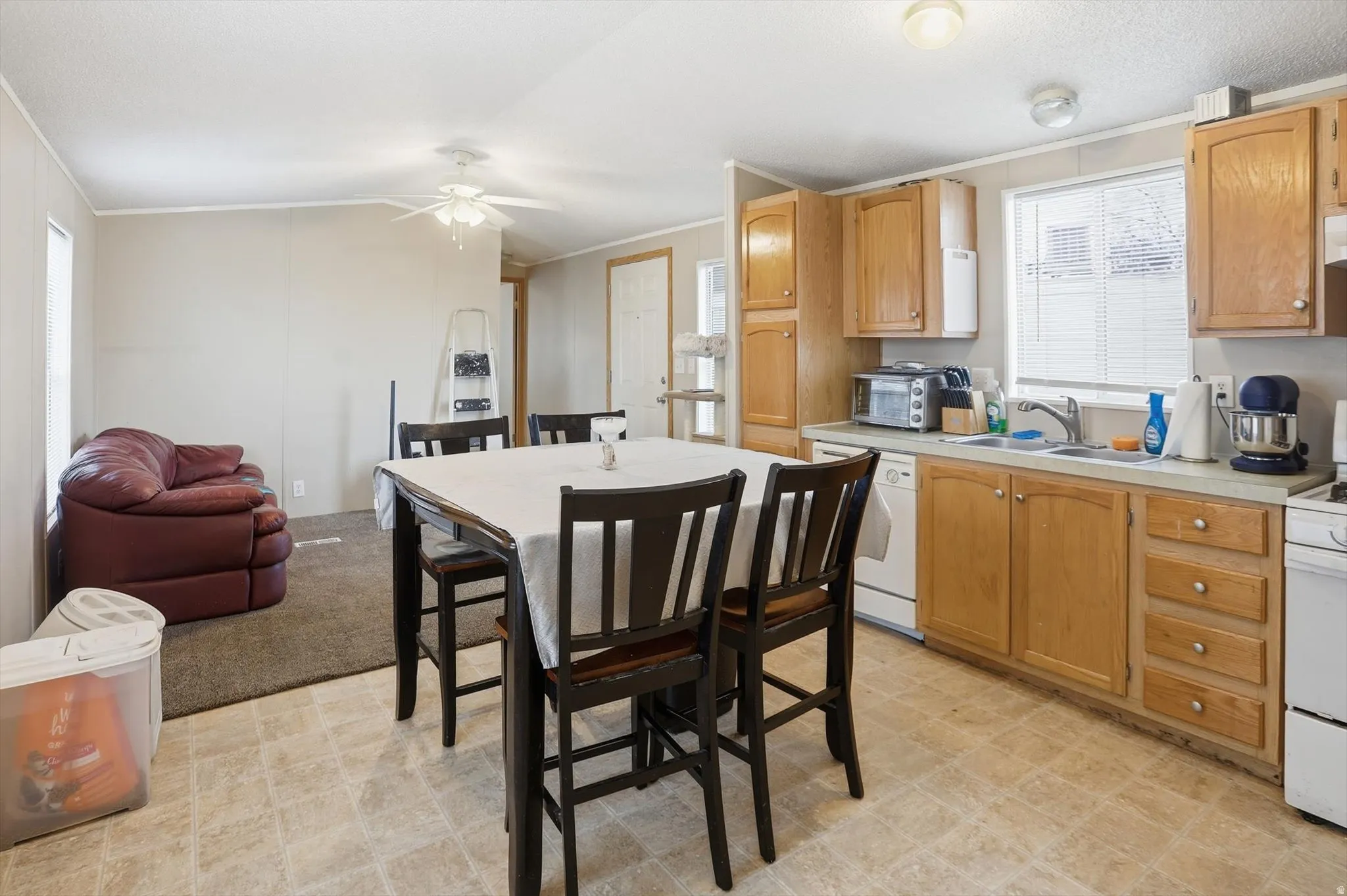 Kitchen featuring light countertops, ornamental molding, white appliances, light flooring, and vaulted ceiling