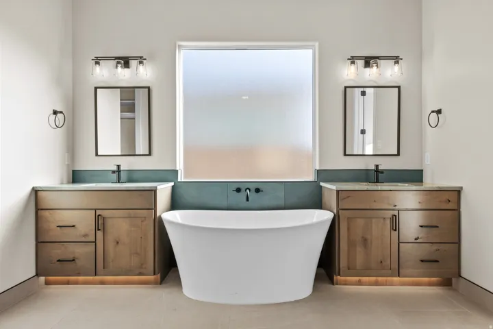 Bathroom featuring two vanities, light tile patterned floors, a soaking tub, and tile walls