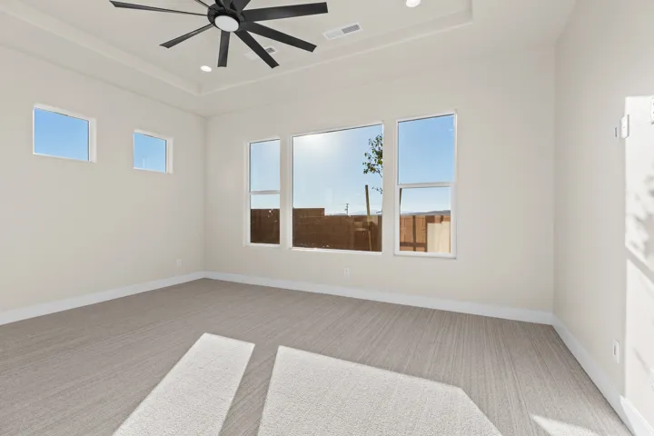 Empty room with light carpet, a ceiling fan, a raised ceiling, and recessed lighting