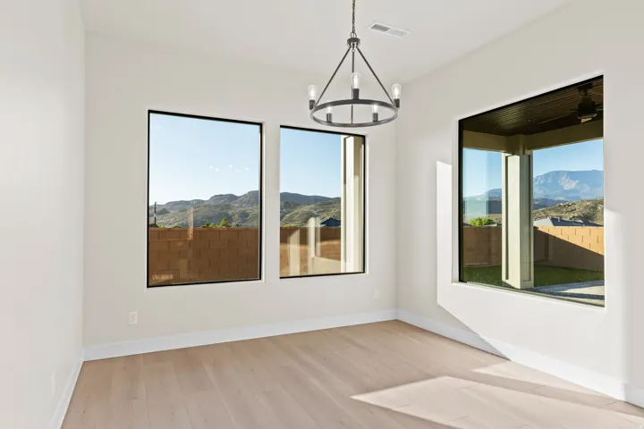 Spare room with light wood finished floors, a mountain view, and suspended lighting