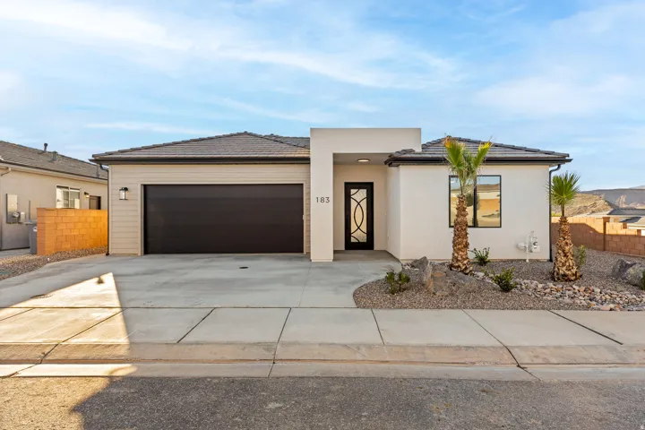View of front of house with an attached garage, driveway, a tile roof, and stucco siding
