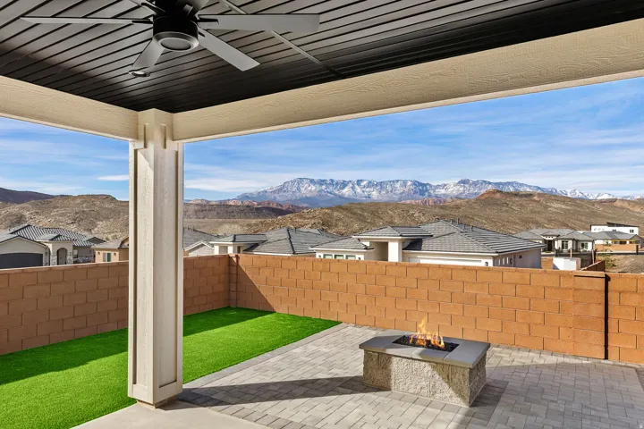 Fenced backyard with ceiling fan, an outdoor fire pit, a mountain view, a patio, and a residential view