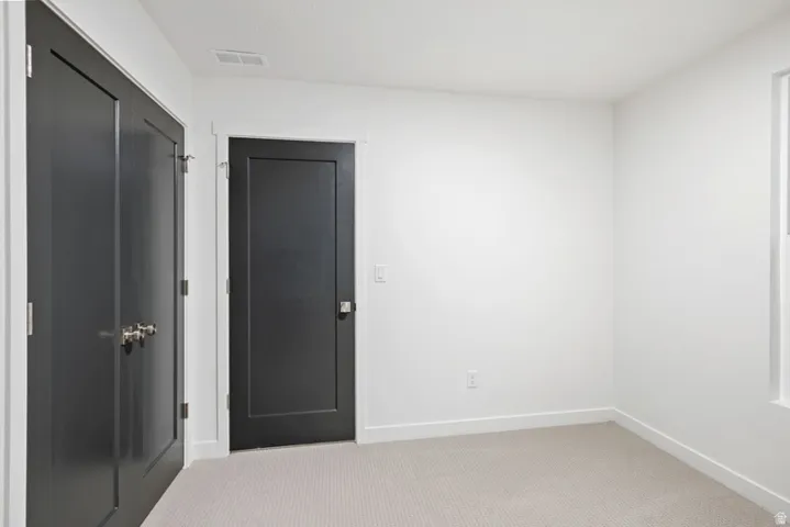 Unfurnished bedroom with light colored carpet and a closet