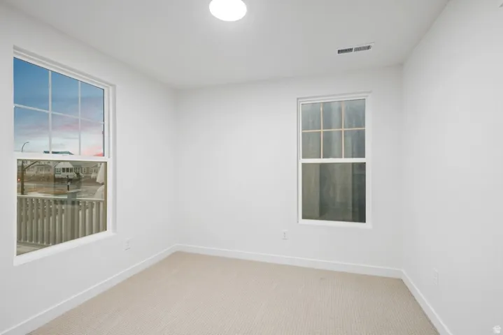 Unfurnished room with light colored carpet and baseboards