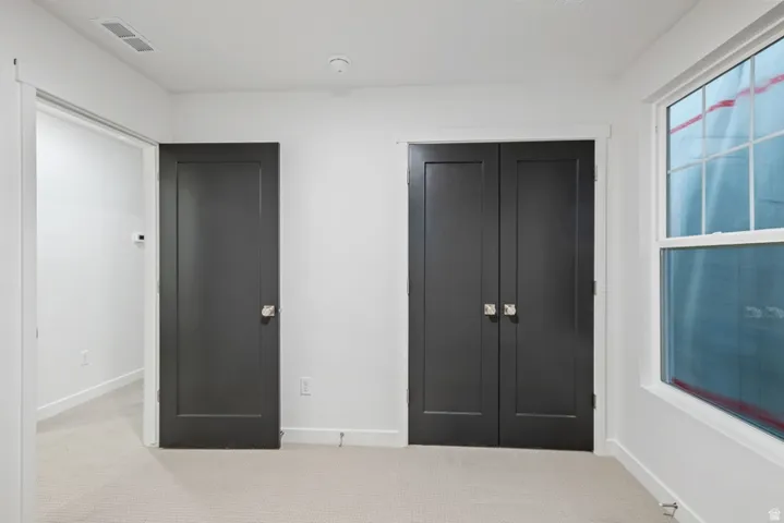 Unfurnished bedroom with light carpet and a closet