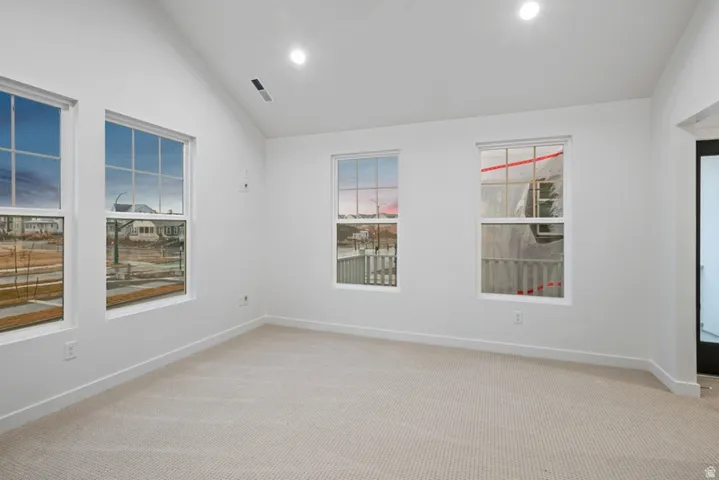 Unfurnished room featuring lofted ceiling, light carpet, and recessed lighting