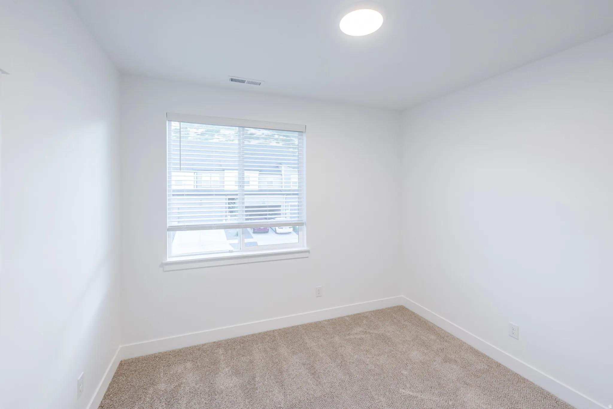 Recessed ceiling lighting, neutral carpet, white walls, and a window with horizontal blinds