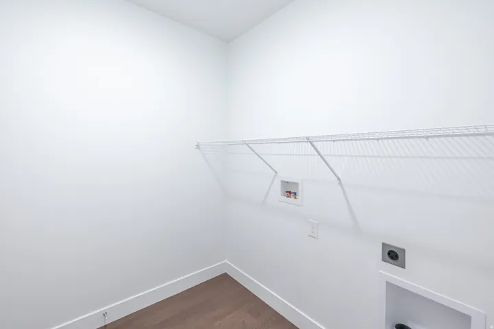 White wire shelving with laundry hookups and utility outlet, complemented by wood-finish flooring