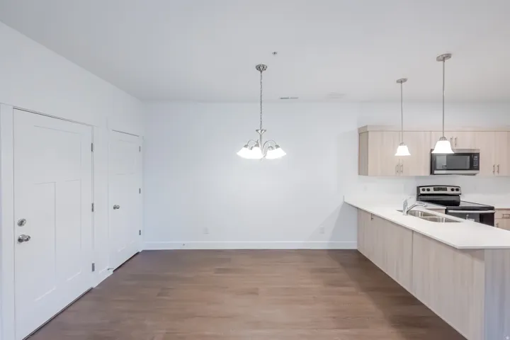 Open-concept living space with wood-finish flooring, white walls, and a modern kitchen
