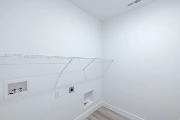 Wire shelving, wall-mounted utilities, light-toned walls, and wood-finish flooring