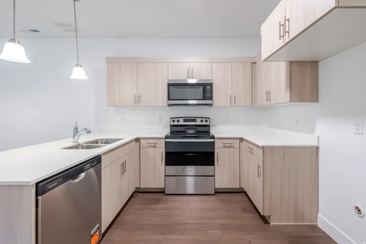Kitchen featuring wood-finish cabinetry, light-toned countertops, and wood-finish flooring