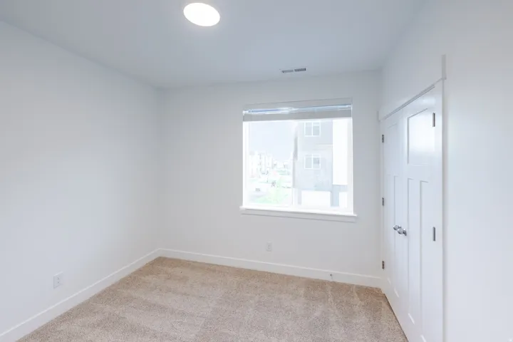 Neutral carpet flooring, white walls, and a contemporary flush-mount ceiling light