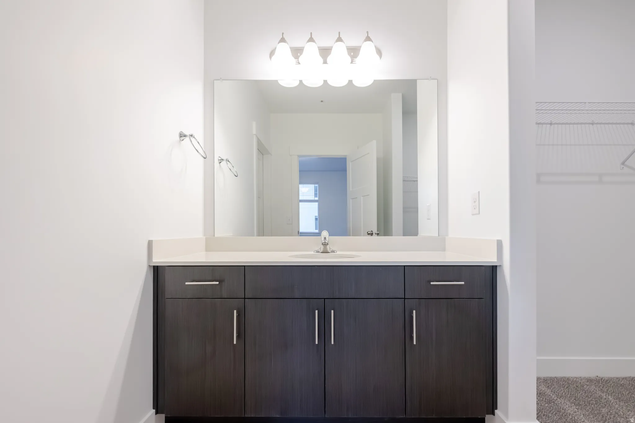 Modern vanity with a light-toned countertop, integrated sink, and an overhead light fixture