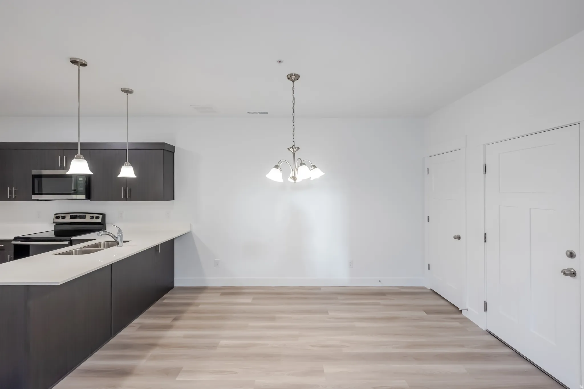 Kitchen featuring dark cabinetry, stainless steel appliances, white countertops, and wood-finish flooring