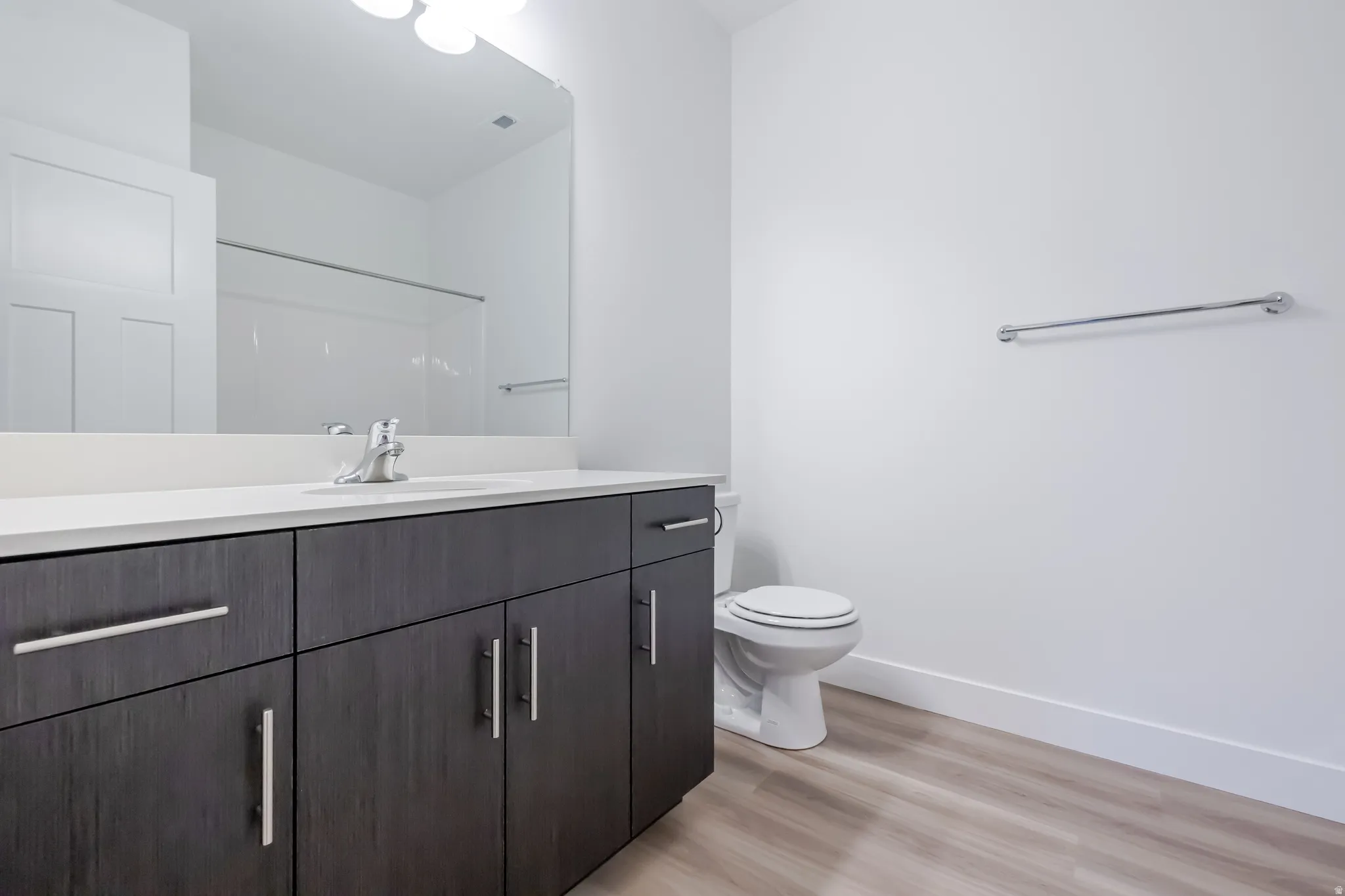 Contemporary vanity with dark wood-finish cabinetry, white countertop, and integrated sink