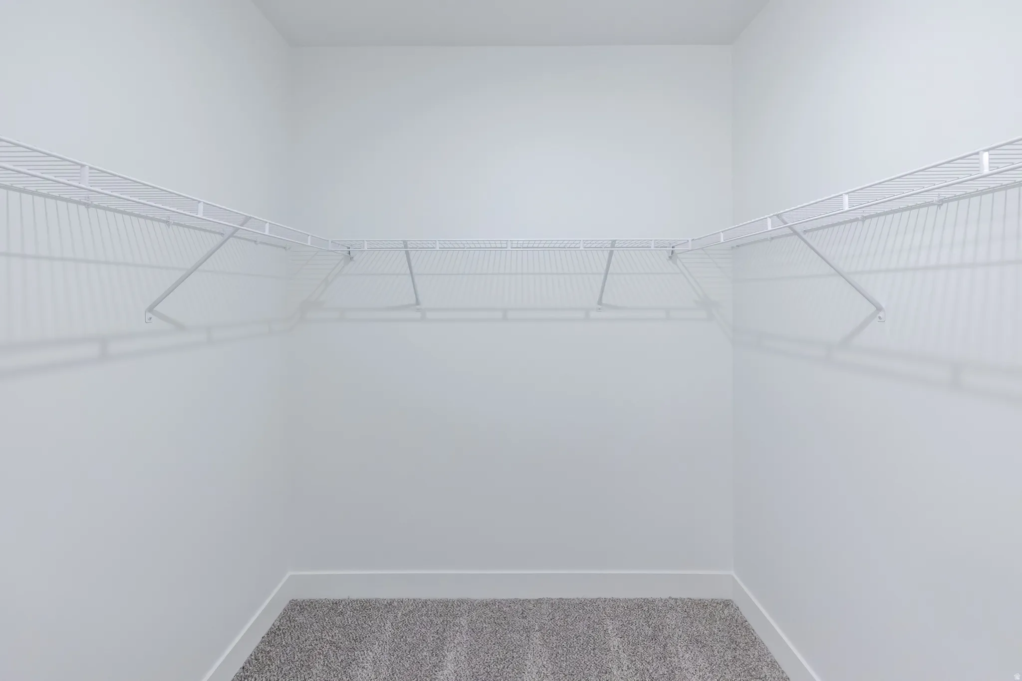 Wall-to-wall wire shelving, L-shaped shelving configuration, and gray carpeting