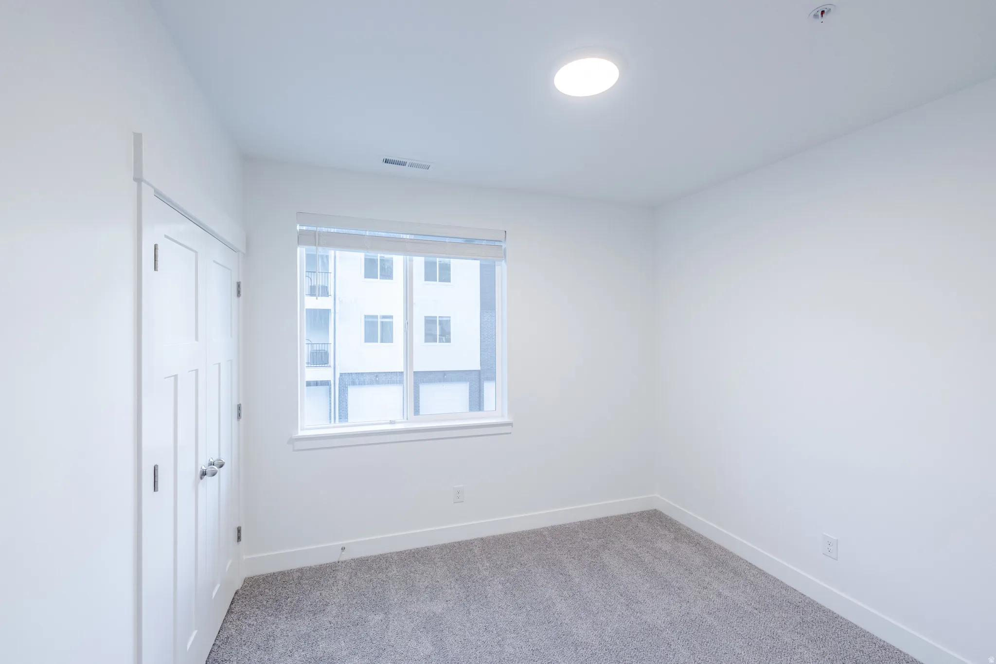 Recessed lighting, window with blinds, dual closet doors, and gray carpeting