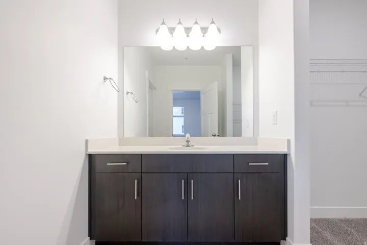 Modern vanity with a light-toned countertop, integrated sink, and an overhead light fixture