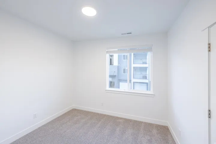 Recessed ceiling light fixture, neutral carpet, white walls, and white window trim