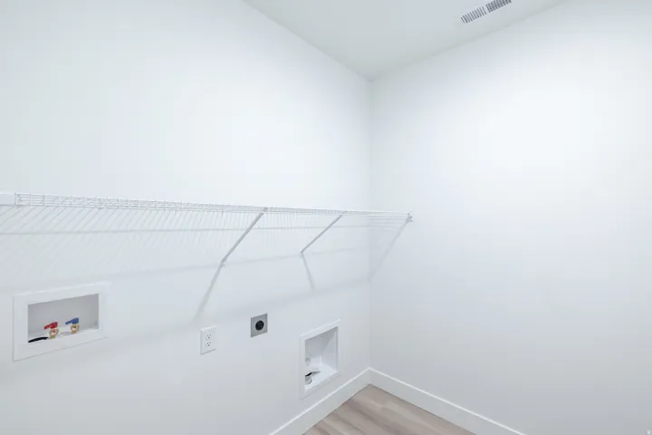White wire shelving, a wall-mounted laundry hookup, and wood-finish flooring