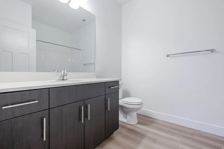 Contemporary vanity with dark wood-finish cabinetry, white countertop, and integrated sink
