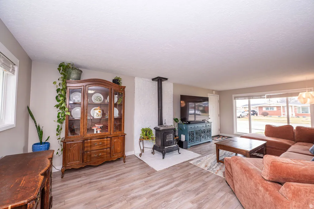 Living area with light wood finished floors, a wood stove, and a textured ceiling