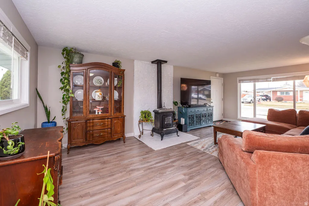 Living area featuring a wood stove, light wood-style floors, and a textured ceiling