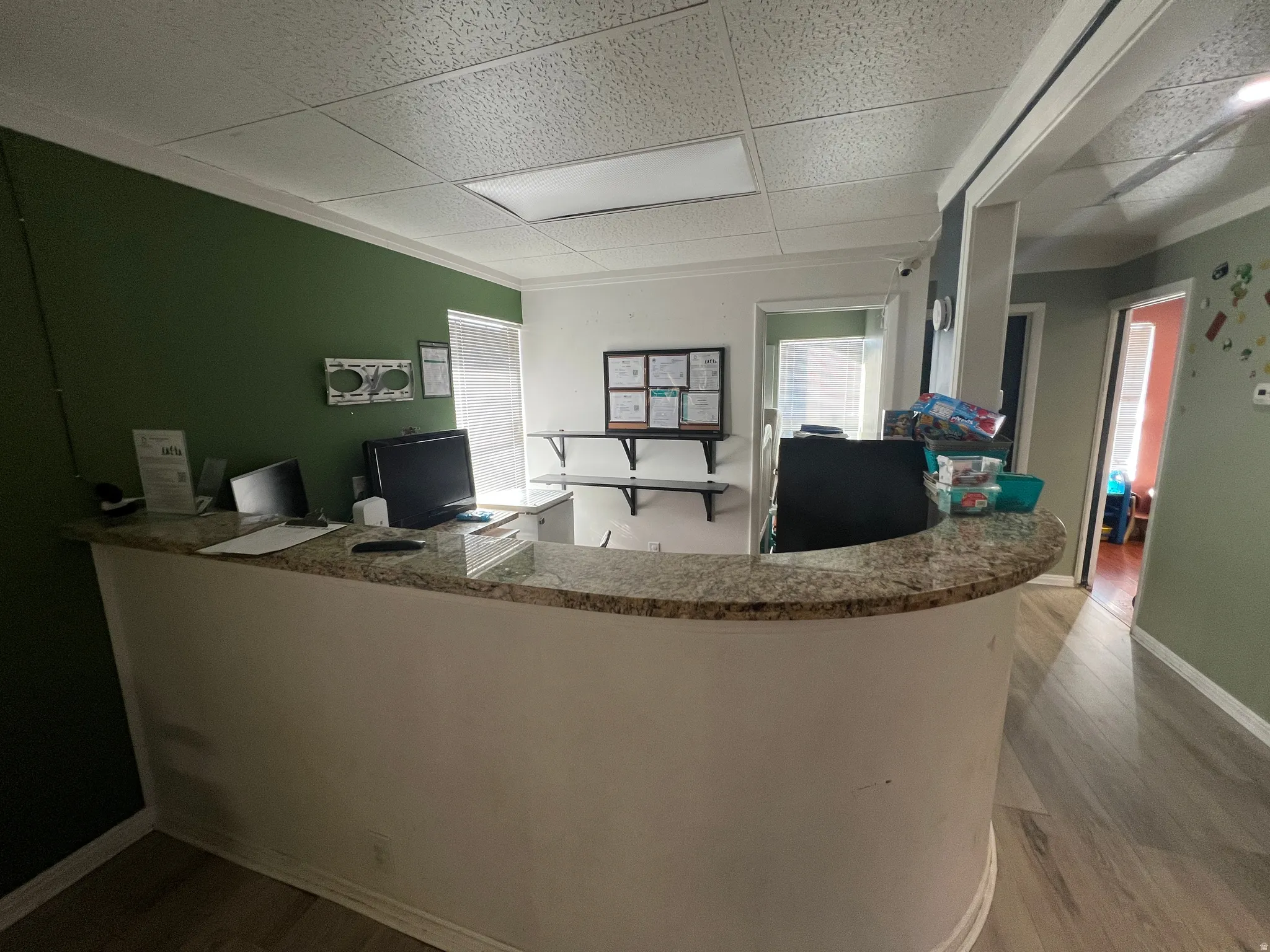 Office area featuring light wood-style flooring, a paneled ceiling, and plenty of natural light
