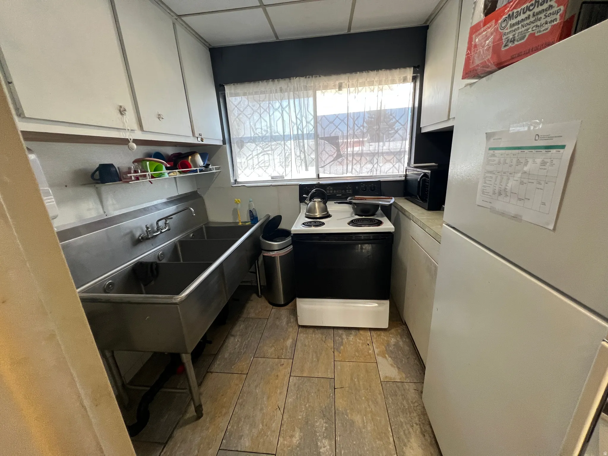 Kitchen with white appliances, light wood-type flooring, light countertops, and white cabinets