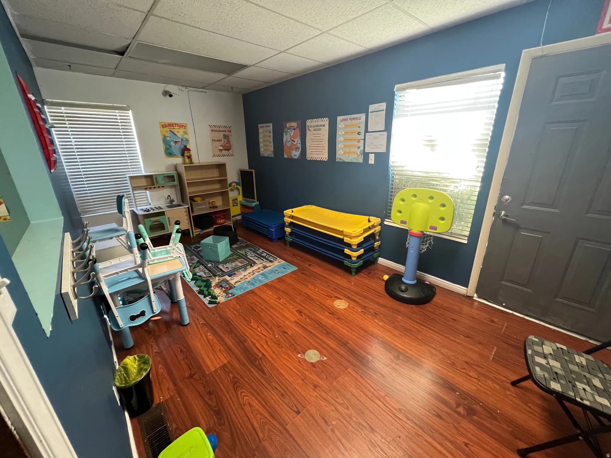 Game room with a paneled ceiling and dark wood-style flooring