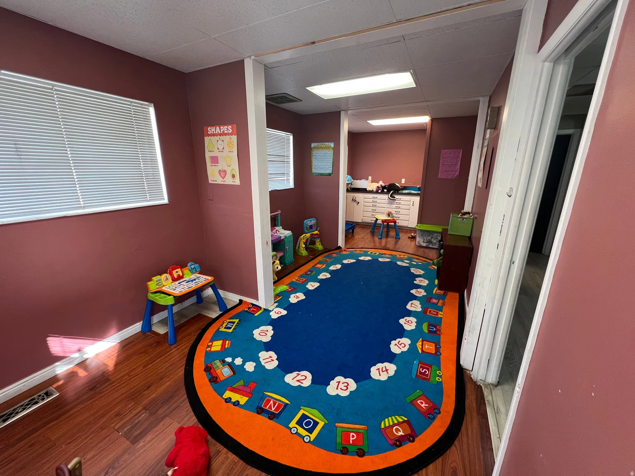Recreation room featuring dark wood-type flooring and a paneled ceiling