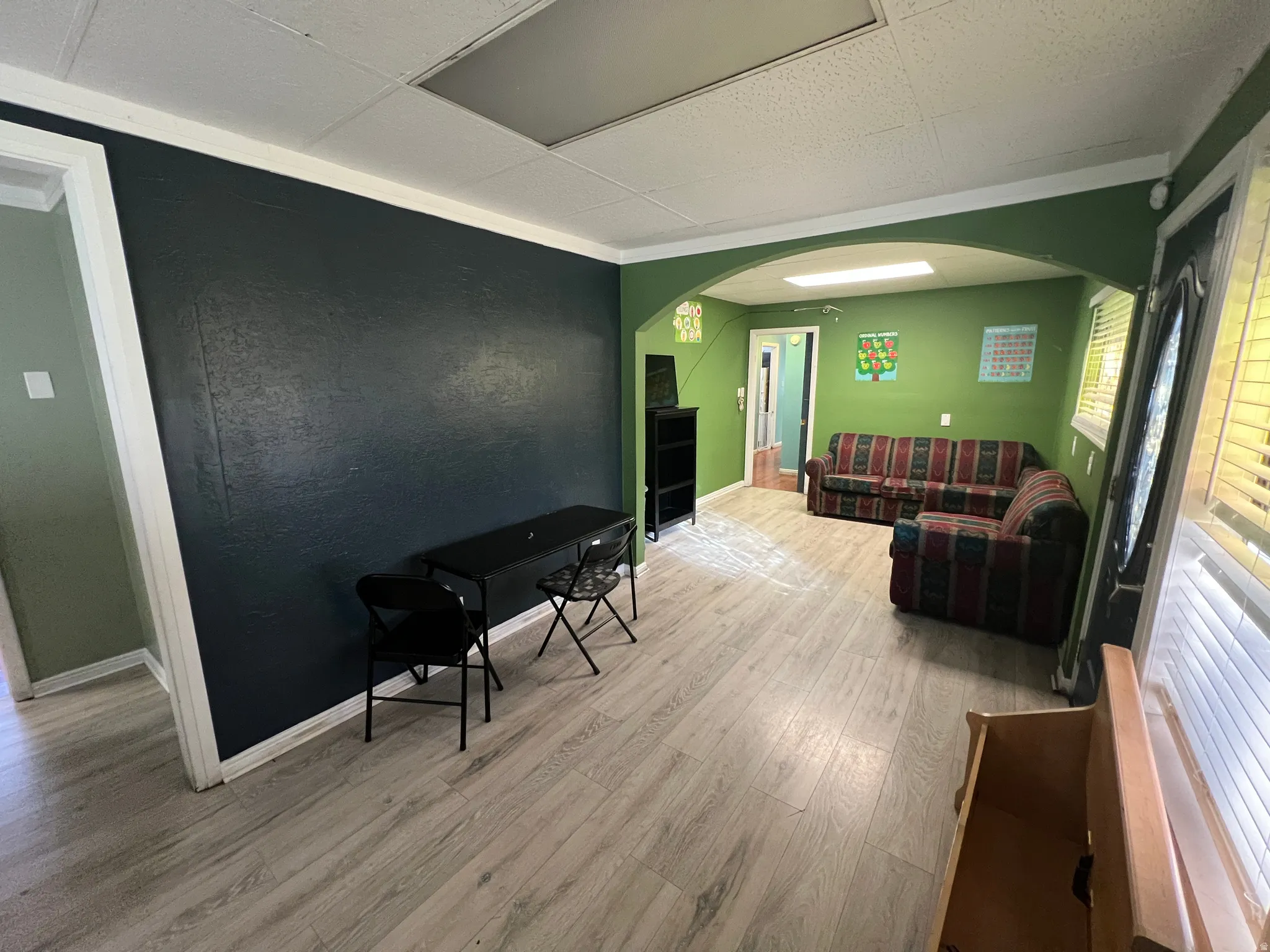 Living area with arched walkways, light wood finished floors, an accent wall, and a textured wall