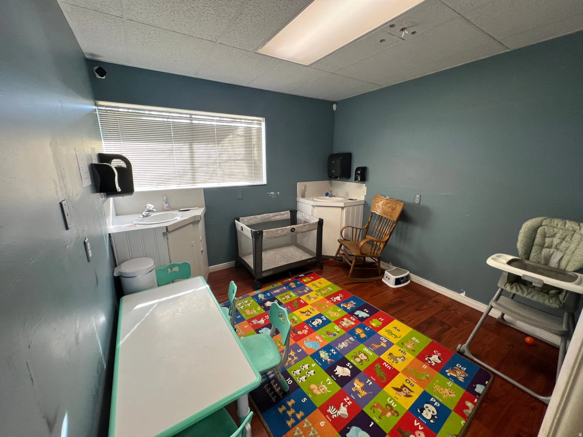 Playroom with dark wood finished floors and a paneled ceiling