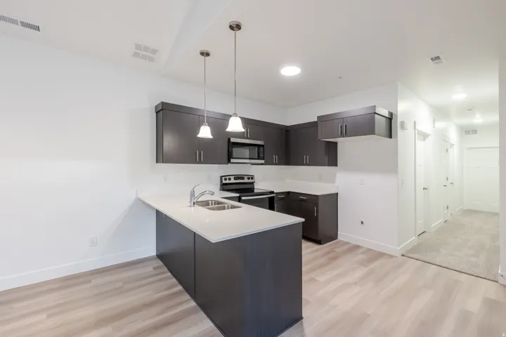 Kitchen featuring dark wood-finish cabinetry, light countertops, and stainless steel appliances