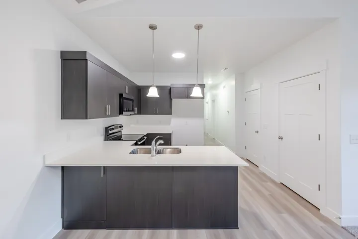 Kitchen featuring dark wood-finish cabinetry, light-toned countertops, and stainless steel appliances