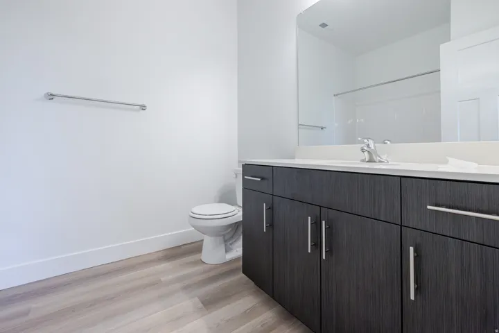 Modern bathroom vanity with wood-finish cabinetry, white countertop, and integrated sink